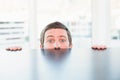 Nervous businessman peeking over desk