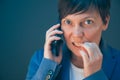 Nervous businesswoman bites fingernails during telephone conversation Royalty Free Stock Photo