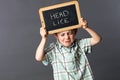 Nervous child holding a stressful head lice slate to protest