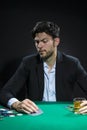 Nervous and Concentrated Handsome Caucasian Brunet Young Pocker Player At Pocker Table With Chips While Drinking Alcohol While Royalty Free Stock Photo