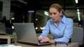 Nervous female working on laptop at night, stressful job causing health problems