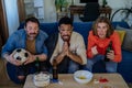 Nervous football fans friends staring at TV and watching football match at home