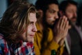 Nervous football fans friends watching match on TV at home and praying.