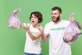 Nervous friends couple in volunteer t-shirt isolated on green background. Voluntary free work assistance help charity