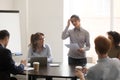 Indian presenter speaker stands in front of colleagues in meeting