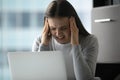 Nervous lady office worker hugging head in panic before laptop