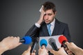 Nervous man is afraid of public speech and sweating. Many microphones in front Royalty Free Stock Photo
