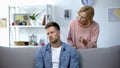 Nervous mother talking to adult son sitting on sofa at home, family conflict Royalty Free Stock Photo