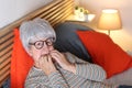 Nervous senior woman bitting nails in bed