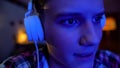 Nervous teenager in headphones playing video games on laptop, extreme close-up