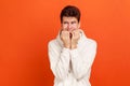 Nervous terrified teenager in white casual style sweatshirt biting his fingers with shocked look, fears and phobias