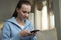 Nervous, thoughtful young brunette in a blue sweater, worried, uses the phone while sitting at home on the couch Royalty Free Stock Photo