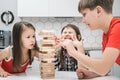 Nervous worried passionate kids playing board balance wooden brick tower game. Boy trying to move wooden cube out line Royalty Free Stock Photo