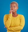 Nervous, worried and scared black woman in fear and bitting nails isolated against a studio blue background. Mental Royalty Free Stock Photo