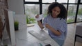 Nervous young African American woman tearing paper sitting at table in home office. Portrait of beautiful overburdened