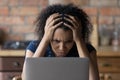 Nervous young african female scratch head stare at laptop screen