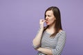 Nervous young brunette woman girl in casual striped clothes posing isolated on violet purple background studio portrait Royalty Free Stock Photo