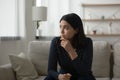 Nervous young mixed race asian woman sitting alone on sofa.