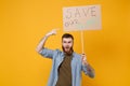 Nervous young protesting man pointing index finger on protest sign broadsheet placard on stick isolated on yellow