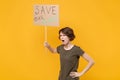 Nervous young protesting woman hold protest sign broadsheet placard on stick isolated on yellow background studio