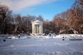 A white gazebo in a winter park, clear blue sky, snow covered space and snow white treed