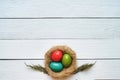 Nest colored eggs wreath on white wooden planks background