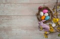 Nest with eggs, chick, pink easter bunny and Forsythia branches with flowers on a wooden background.