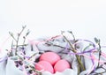 Nest of fabric with pink Easter eggs decorated with silk ribbons and pussy willow on white. Royalty Free Stock Photo