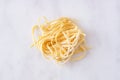 Fresh linguine pasta, top view against white marble