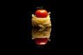 Nest pasta with red tomato black background Royalty Free Stock Photo