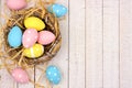 Nest side border with pink, yellow & blue Easter Eggs against white wood Royalty Free Stock Photo