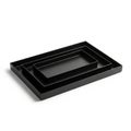 Nested black rectangular trays are arranged concentrically on a white Royalty Free Stock Photo