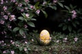 A yellow easter egg in a nest surrounded by pink flowers.