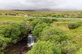 Nestled in lush greenery, Lealt Falls on Skye create a tranquil haven, complemented by a countryside road