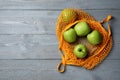 Net bag with fresh green apples on grey wooden table, top view. Space for text Royalty Free Stock Photo