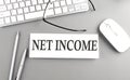 NET INCOME text on paper with keyboard on grey background