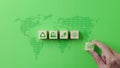 Net zero emission and carbon neutral 2050 concept. Hand puts wooden cube block with net zero icons on world map green background. Royalty Free Stock Photo
