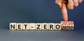 Net-zero 2030 symbol. Concept words Net-zero 2030 or Net-zero 2050 on wooden cubes. Businessman hand. Beautiful grey background.