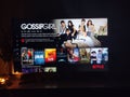 Netflix app on tv screen playing and the `Gossip Girl` series logo behind