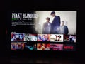 Netflix app on tv screen playing and the `Peaky Blinders ` series logo behind. Royalty Free Stock Photo