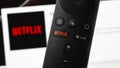 Netflix red button on the remote controller on display notebook background. Royalty Free Stock Photo