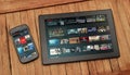 Netflix in a tablet and smartphone, both over the wooden table.