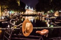 NETHERLANDS, AMSTERDAM - 23 AUG 2018: Night city view of bicycle with Hat on helm on Amsterdam bridge and typical dutch