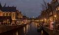 Netherlands, Amsterdam - December 6, 2017, Amsterdam canal at night, light reflection on water, boats and bicycles Royalty Free Stock Photo