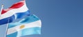 Netherlands and Argentina flags fluttering in the wind against a blue sky mockup with copy space. Amsterdam, Buenos Aires national Royalty Free Stock Photo