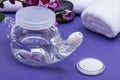 Neti Pot with Soft Comfort Tip, pile of Saline, Purple Orchid Flowers and rolled up White Towels on purple background. Sinus wash. Royalty Free Stock Photo