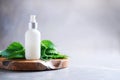 Nettle lotion, cream, shampoo or soap in white bottle and fresh nettles leaves on grey background. Medicinal herb for health and