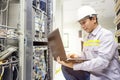 Network administrator holding laptop in hand working Configuration with core switch on rack cabinet in data center