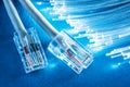 Network cables and bundle of optical fibers with lights in the ends. Blue background Royalty Free Stock Photo