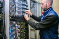 Network engineer switches power cables in the server room rack. The system administrator works in the data center. Portrait of a Royalty Free Stock Photo